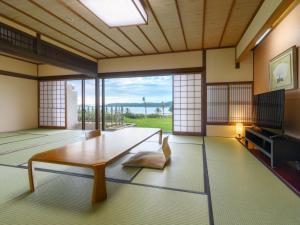 a living room with a table and a tv at Hotel Nishinagato Resort in Takibe