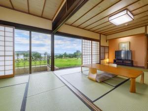 a room with a table and a large window at Hotel Nishinagato Resort in Takibe