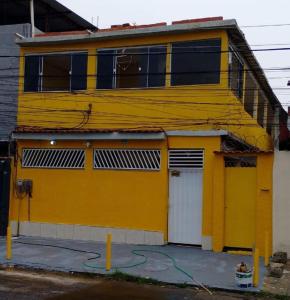 a yellow building with a white door at Recanto Carioca Aconchegante in Rio de Janeiro