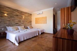 a bedroom with two beds and a brick wall at Pousada Refugio Jardim de Canoa in Canoa Quebrada +31 photos