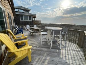 a deck with chairs and a table and a table and chairs at 57151 Lighthouse Rd Home in Hatteras