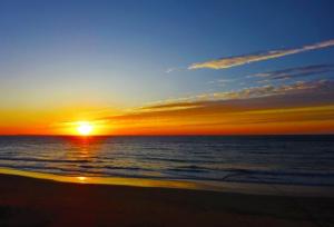 a sunset on the beach with the ocean at Jupiter 糸島市1棟貸し切り宿 in Itoshima