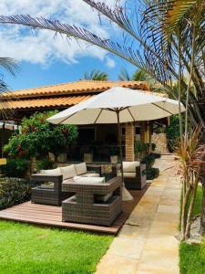 a patio with an umbrella and tables and chairs at Pousada Refugio Jardim de Canoa in Canoa Quebrada