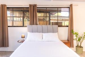 a bedroom with a white bed with a large window at Nosara Hotel Playa Garza in Garza +62 photos