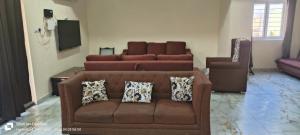 a living room with a brown couch with pillows at Sakez Homestays HH in Hyderabad