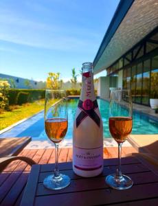 two glasses of wine on a table with a bottle of wine at 913 Luxury Pool Villa Khaolak in Khao Lak