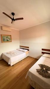 two beds in a room with a ceiling fan at Hotel Pousada Dona Ana in Aparecida