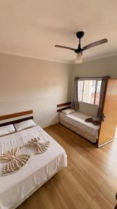 a bedroom with two beds and a ceiling fan at Hotel Pousada Dona Ana in Aparecida