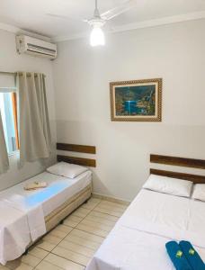 a bedroom with two beds and a picture on the wall at Hotel Pousada Dona Ana in Aparecida +9 photos