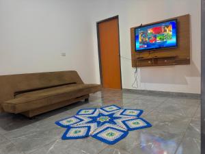 a living room with a couch and a flat screen tv at Casa Grande e Climatizada in Campo Grande