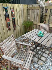 a wooden table and two chairs next to a fence at Centrally located peaceful place in Greymouth