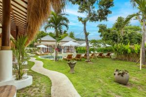 a resort yard with chairs and a swimming pool at Roh Villas Kuta Lombok in Kuta Lombok