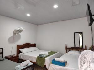 a bedroom with two beds and a fan at Casa Hotel Bijaos in Mompós