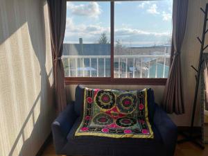 a pillow on a couch in front of a window at Nomad Gala Otaru in Otaru
