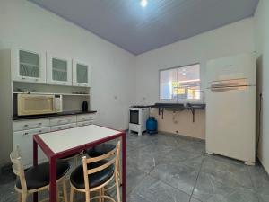 a kitchen with a refrigerator and a table with chairs at Casa Grande e Climatizada in Campo Grande