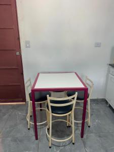 a red table with two chairs and a table with a counter at Casa Grande e Climatizada in Campo Grande +8 photos