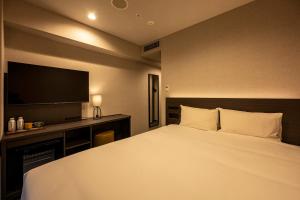 a hotel room with a bed and a television at THE KNOT FUKUOKA Tenjin in Fukuoka