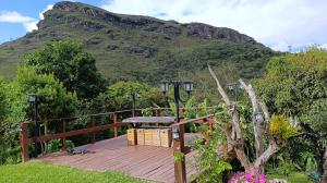 a cat sitting on a wooden deck in front of a mountain at Chalé da Ana in Ouro Preto