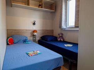 two beds in a room with blue sheets and stuffed animals at Cottage avec clim - 4 pers. - API-1-52-2191 in Balaruc-les-Bains +16 photos