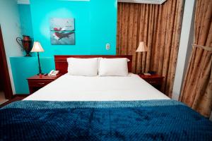 a bedroom with a bed with a blue wall at Quo Vadis Hotel in Loja