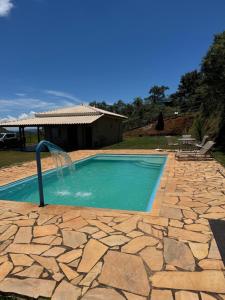 a swimming pool with a fountain on a stone patio at Sítio com piscina em bh mirante do Sol in Santa Luzia