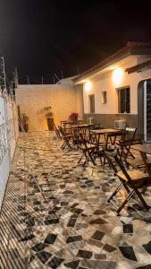 a group of wooden tables on a patio at night at Hotel Pousada Dona Ana in Aparecida