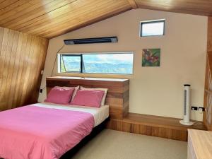 a bedroom with a bed with pink sheets and a window at Whangaroa Barn in Whangaroa