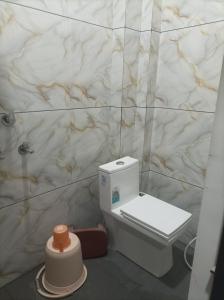 a white toilet in a bathroom with a marble wall at आदिनाथ गेस्ट हाउस in Ujjain +2 photos