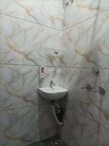 a white sink in a bathroom with marble walls at आदिनाथ गेस्ट हाउस in Ujjain