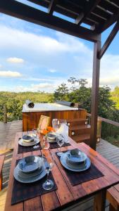 a wooden table with plates and wine glasses on a deck at Cabana Janela do Céu in Jaboticatubas