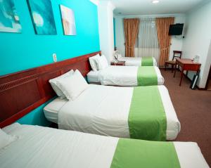 a hotel room with three beds and a blue wall at Quo Vadis Hotel in Loja