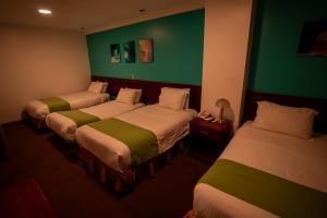 two beds in a hotel room with green walls at Quo Vadis Hotel in Loja
