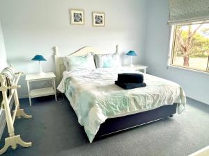a bedroom with a bed and two lamps and a window at Bay-Ann Cottage in Kingscote