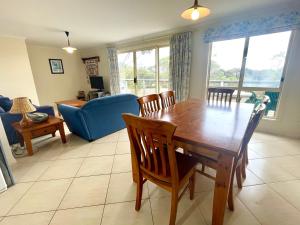 a living room with a wooden table and chairs at Bay-Ann Cottage in Kingscote +2 photos