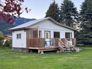 a small white house with a deck in a field at Harrison Hammond House Farmstay in Harrison Mills