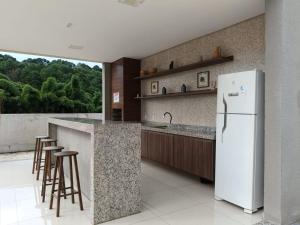 a kitchen with a white refrigerator and bar stools at Lua da Mantiqueira - Staffy House Extrema in Extrema