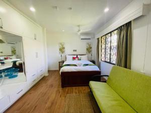 a bedroom with a bed and a green couch at Residence71Nadi Fiji in Nadi
