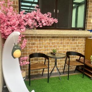two chairs and a table on a patio with pink flowers at 精彩奇寓站前電梯主題民宿走路到車站好停車 in Hualien City