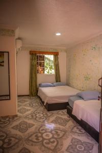 a bedroom with two beds and a window at POSADA NATIVA DERMA´S INN in San Andrés