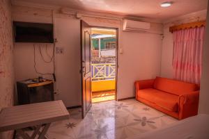 a living room with an orange couch and a window at POSADA NATIVA DERMA´S INN in San Andrés