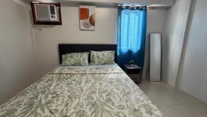 a bedroom with a bed and a blue window at Plumera Mactan Square in Mactan Island