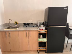 a kitchen with a black refrigerator and a sink at Plumera Mactan Square in Mactan Island