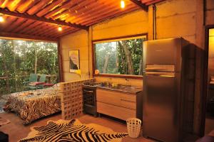 a kitchen with a stainless steel refrigerator and a bed at Casinha Natureza in Brasília