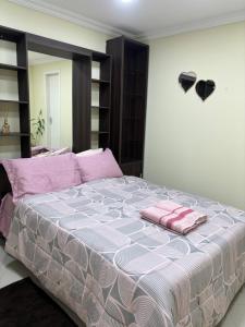 a bedroom with a bed with pink pillows on it at Suíte sossego in Rio das Ostras +4 photos