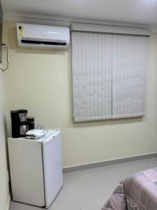 a white room with a window and a refrigerator at Suíte sossego in Rio das Ostras