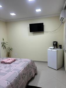 a bedroom with a bed and a tv on the wall at Suíte sossego in Rio das Ostras