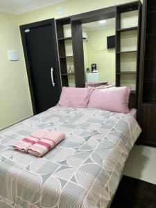 a bedroom with a bed with pink pillows on it at Suíte sossego in Rio das Ostras