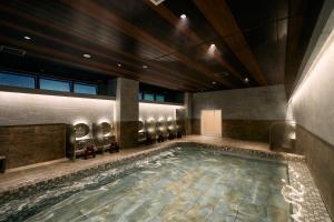 a swimming pool in a hotel room with chairs at COZY HOTEL NUKUI shimanami in Imabari