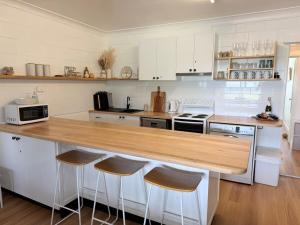 a kitchen with a wooden counter top and bar stools at Family & Couples Beachside Stay Ocean Glimpses 7 day Xmas 2026 available in Brooms Head
