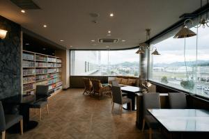 a library with tables and chairs and a large window at COZY HOTEL NUKUI shimanami in Imabari